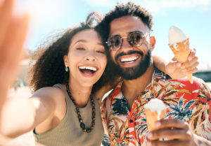 Cropped portrait of an affectionate young couple taking selfies while enjoying ice creams on the beach