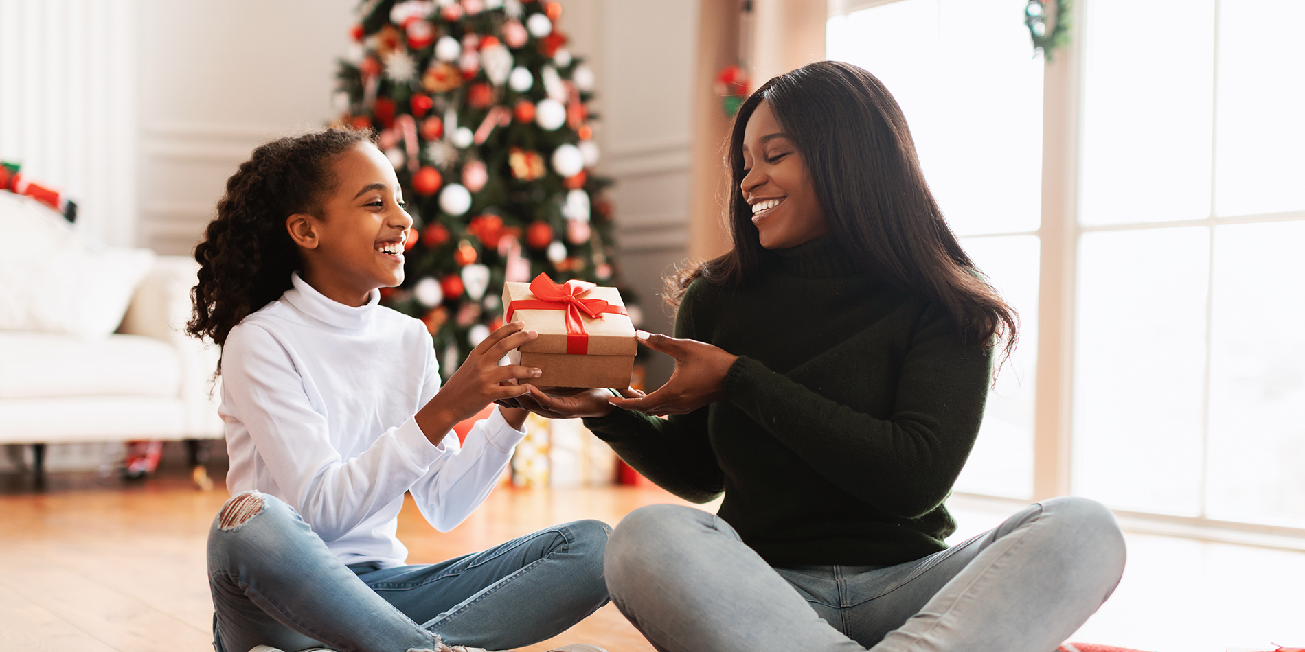 Turn your holiday shopping into rewards - use your debit card and earn with MyCapeRewards. photo of mom and daughter exchanging gifts under a christmas tree